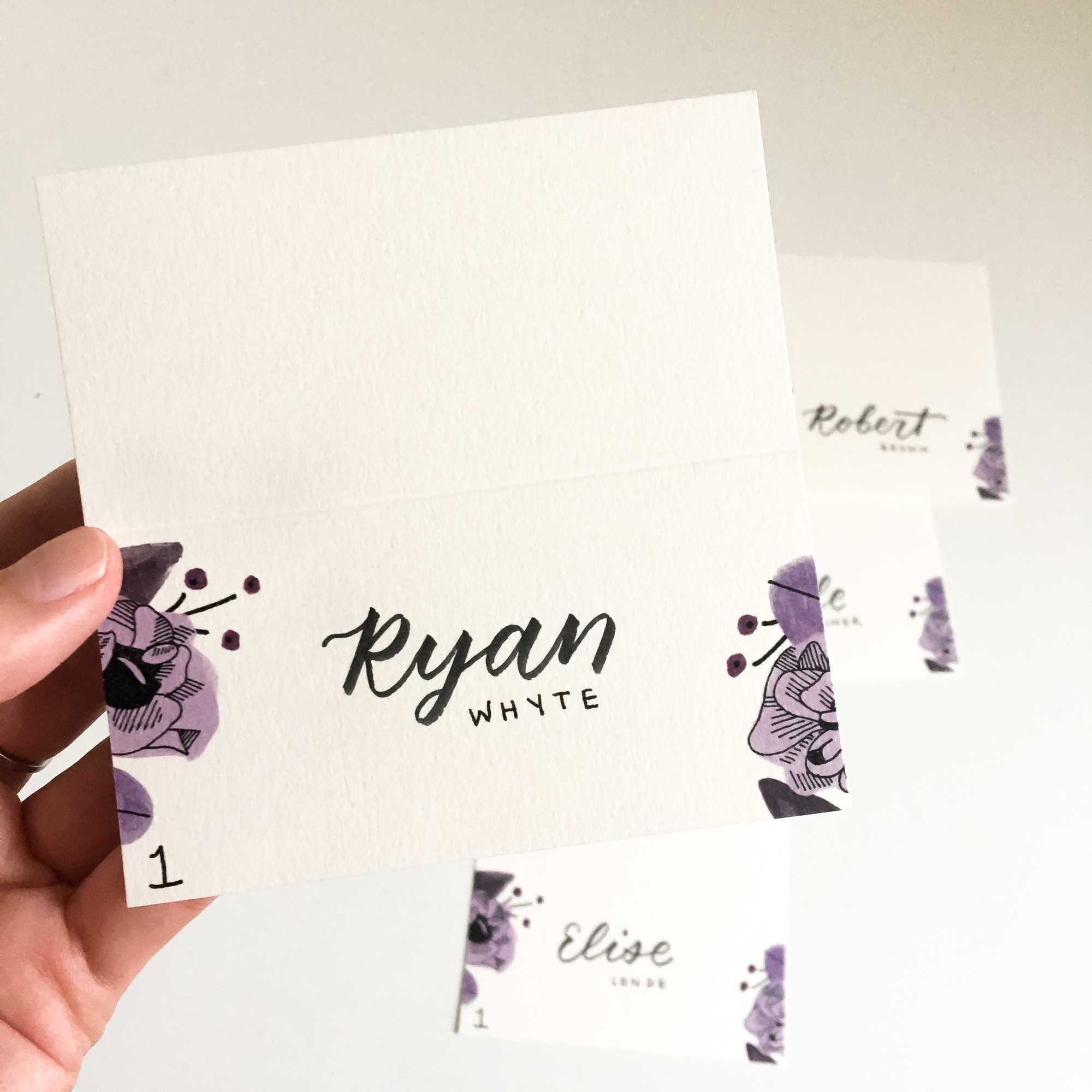Hand holding a place card for Ryan Whyte, table 1